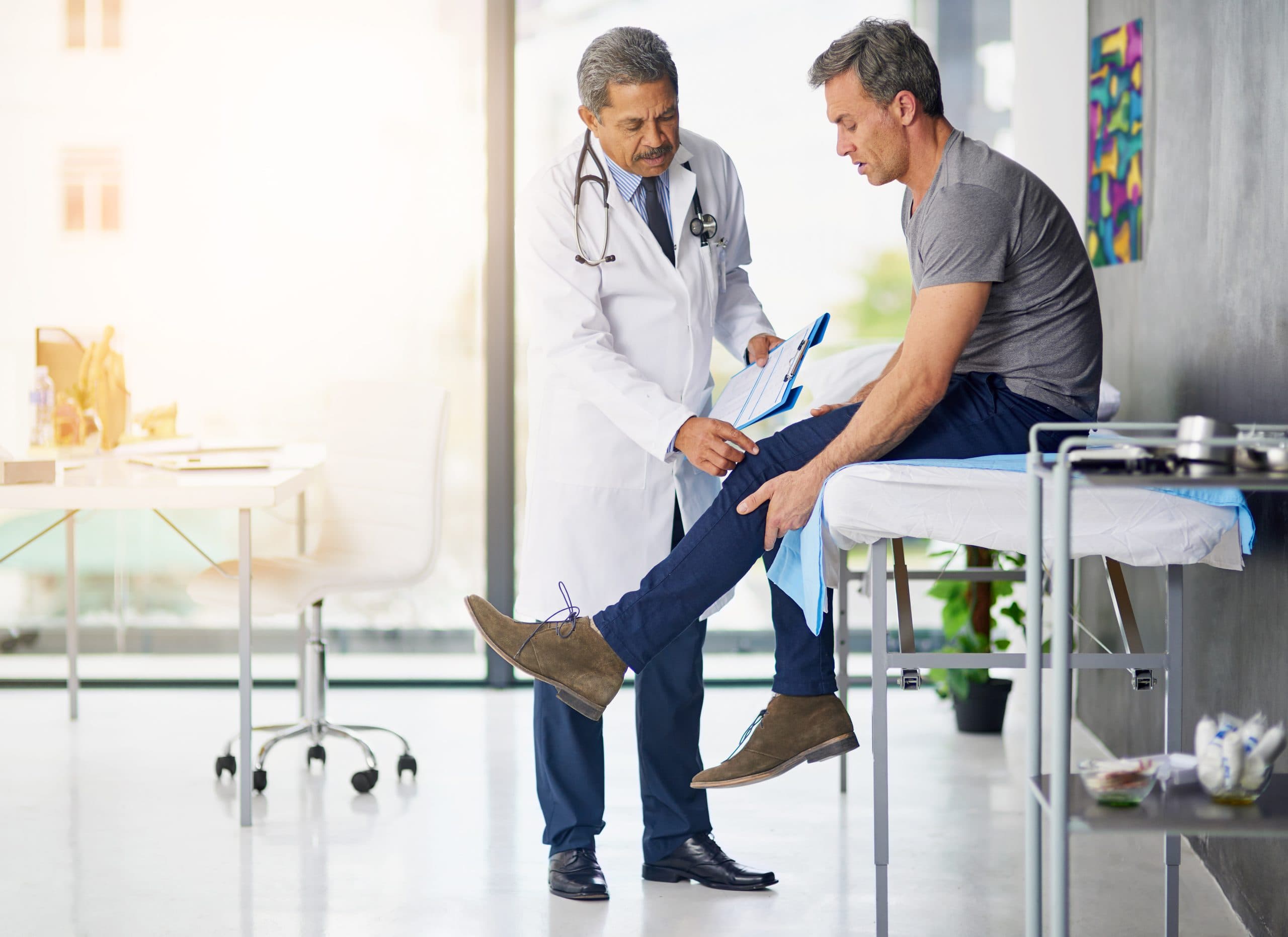 Doctor assessing an older patient's knee during consultation